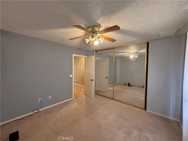 unfurnished bedroom with ceiling fan, light colored carpet, a textured ceiling, and a closet