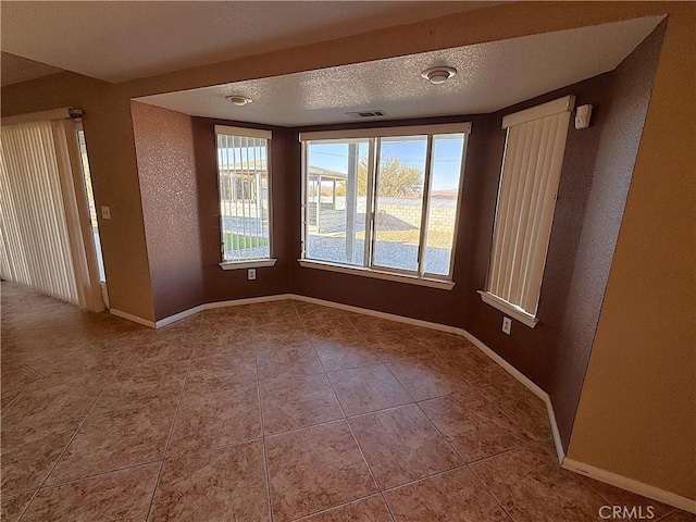 tiled empty room with a textured ceiling