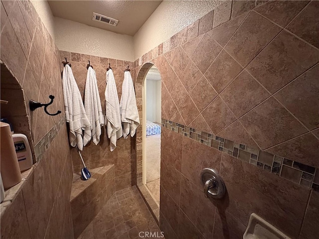 bathroom featuring a textured ceiling and tiled shower