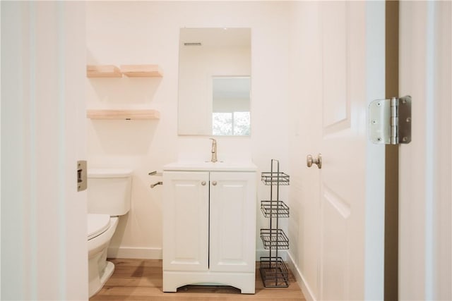 bathroom with hardwood / wood-style flooring, vanity, and toilet