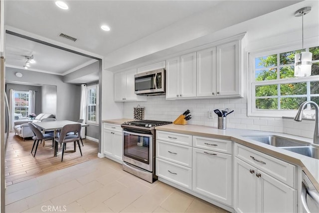 kitchen with white cabinetry, sink, stainless steel appliances, and decorative light fixtures