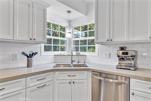 kitchen featuring tasteful backsplash, stainless steel dishwasher, sink, white cabinets, and hanging light fixtures