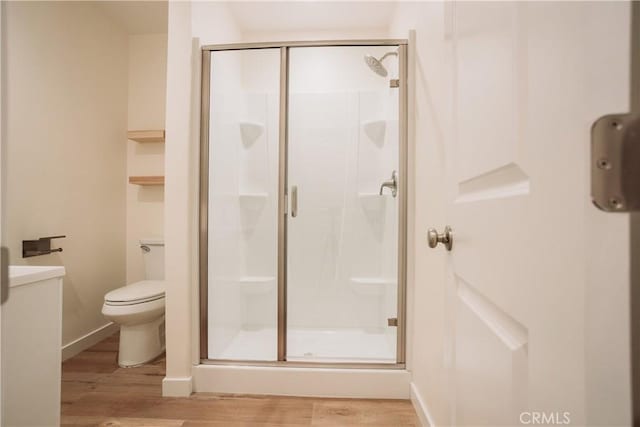 bathroom featuring hardwood / wood-style flooring, toilet, and a shower with shower door