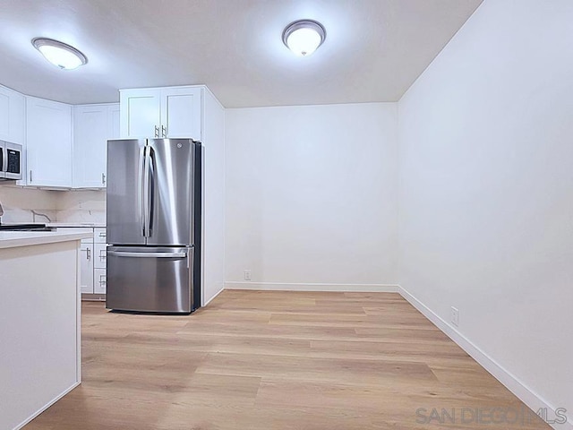 kitchen with white cabinetry, stainless steel appliances, and light hardwood / wood-style flooring