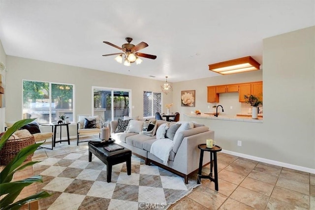 living room featuring ceiling fan with notable chandelier and sink