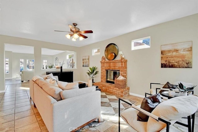 living room with ceiling fan, light tile patterned floors, and a brick fireplace