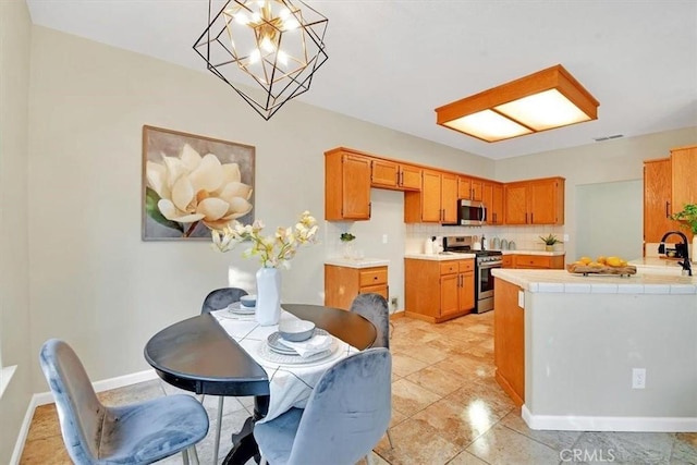 kitchen with a notable chandelier, decorative light fixtures, decorative backsplash, tile counters, and stainless steel appliances