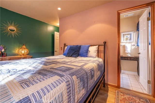 bedroom featuring ensuite bathroom and light hardwood / wood-style flooring