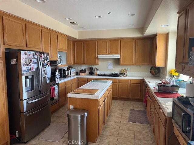 kitchen with tile countertops, a kitchen island, light tile patterned floors, and stainless steel appliances