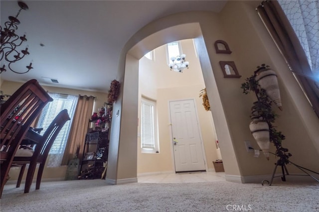 foyer entrance with light colored carpet and an inviting chandelier