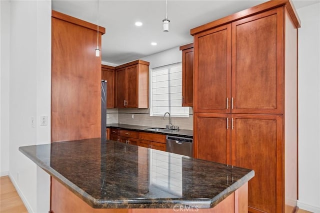 kitchen with sink, dark stone countertops, appliances with stainless steel finishes, tasteful backsplash, and decorative light fixtures