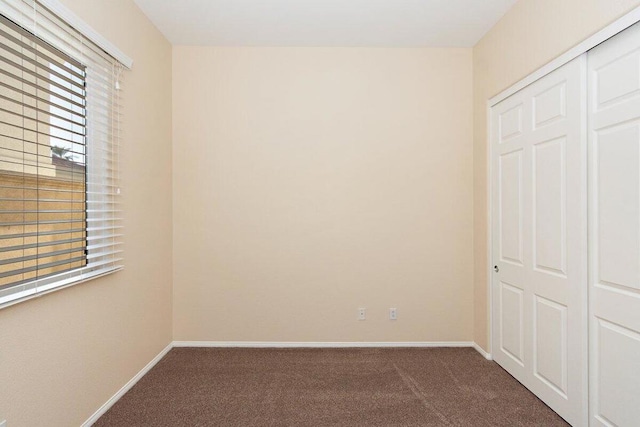 unfurnished bedroom with dark carpet and a closet