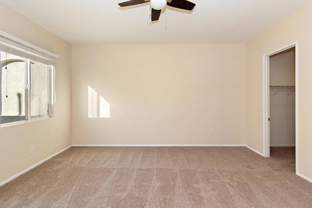 unfurnished bedroom with light carpet, a closet, a spacious closet, and ceiling fan