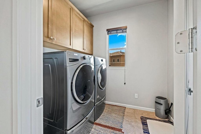 clothes washing area with cabinets, washer and clothes dryer, and light tile patterned flooring