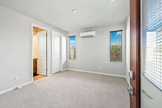 unfurnished bedroom with a wall mounted air conditioner, ensuite bathroom, and light colored carpet