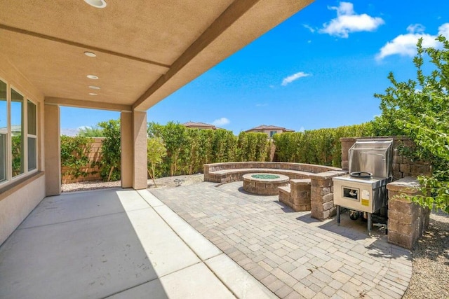 view of patio with an outdoor kitchen and a fire pit