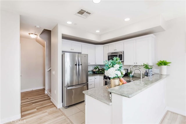 kitchen featuring kitchen peninsula, white cabinetry, light hardwood / wood-style floors, and appliances with stainless steel finishes