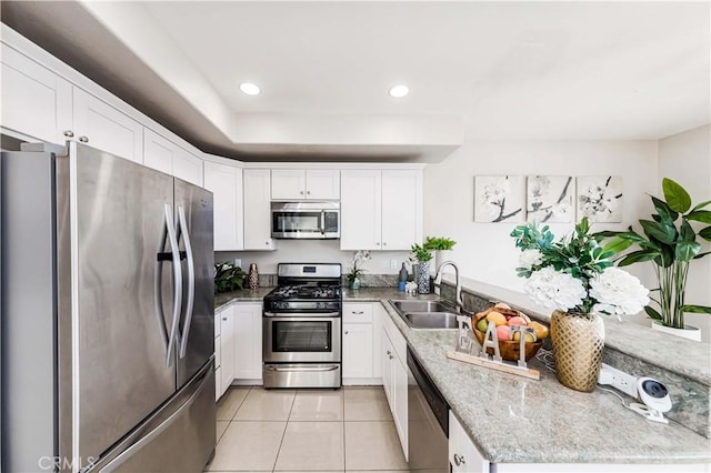 kitchen featuring light stone countertops, sink, light tile patterned flooring, white cabinets, and appliances with stainless steel finishes