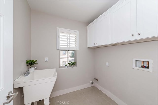 laundry area with cabinets, sink, light tile patterned flooring, and washer hookup