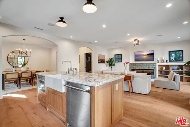 kitchen featuring dishwasher, light brown cabinets, light wood-type flooring, and a fireplace