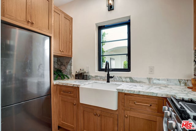 kitchen with light stone countertops, sink, appliances with stainless steel finishes, and tasteful backsplash