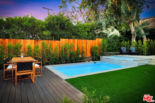 pool at dusk with a lawn and a deck