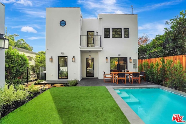 rear view of property with a yard, a patio, a balcony, and a fenced in pool