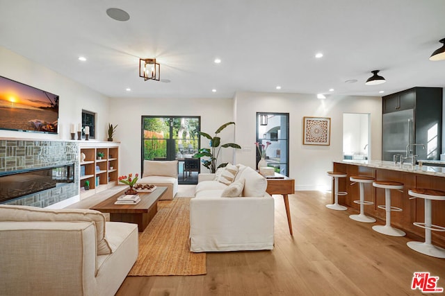 living room with light wood-type flooring, sink, and a chandelier