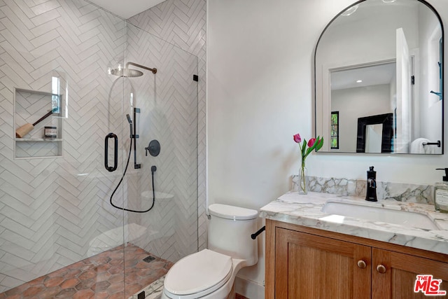 bathroom with walk in shower, vanity, and toilet