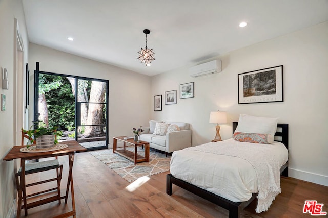 bedroom featuring a wall mounted air conditioner, hardwood / wood-style floors, and access to exterior