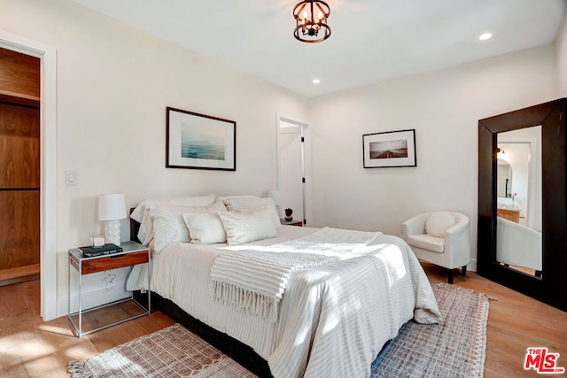 bedroom with a notable chandelier and light wood-type flooring