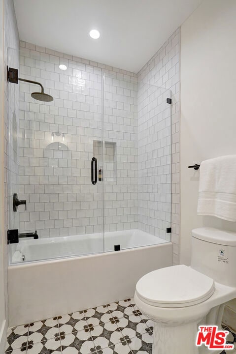 bathroom with tile patterned flooring, enclosed tub / shower combo, and toilet