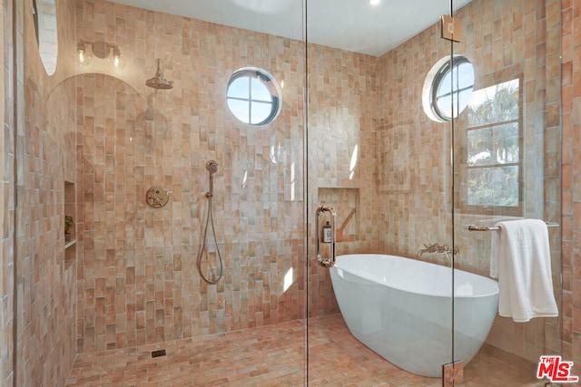 bathroom featuring separate shower and tub, plenty of natural light, and tile walls