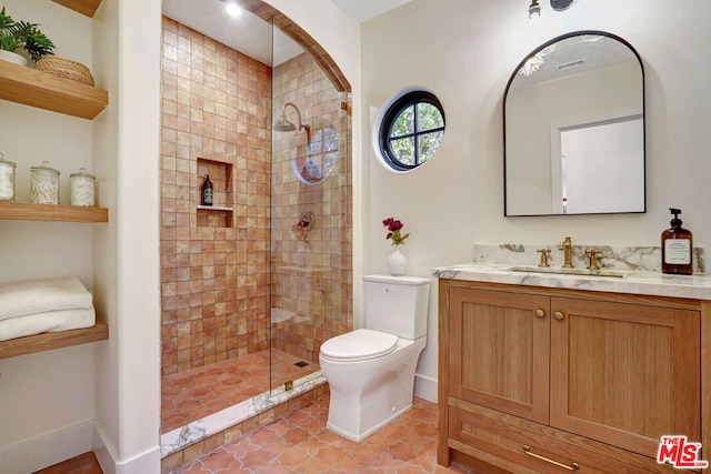 bathroom featuring a tile shower, vanity, toilet, and tile patterned floors