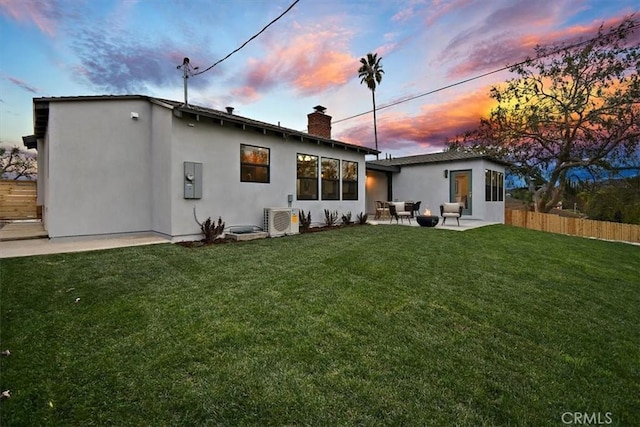 back house at dusk featuring ac unit, a patio area, and a yard