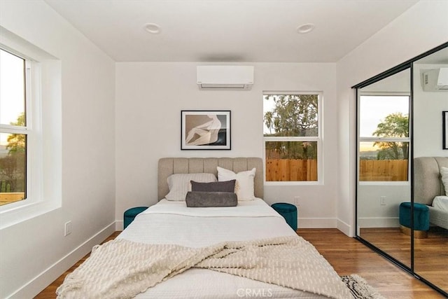 bedroom with a closet, a wall mounted air conditioner, and hardwood / wood-style flooring