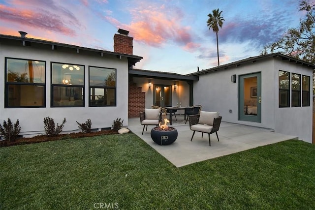 back house at dusk with a yard, an outdoor fire pit, and a patio area