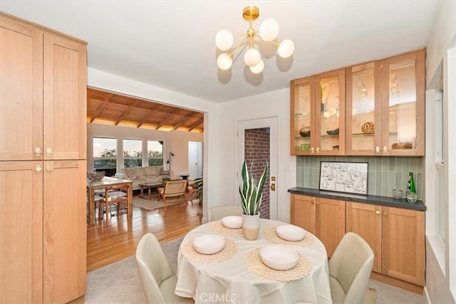 dining space featuring lofted ceiling with beams, an inviting chandelier, wooden ceiling, and light hardwood / wood-style flooring