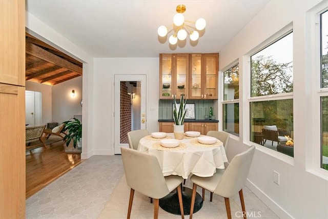 dining room with beamed ceiling, light hardwood / wood-style floors, and a chandelier