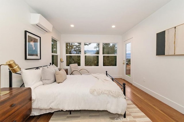 bedroom with an AC wall unit and light hardwood / wood-style flooring