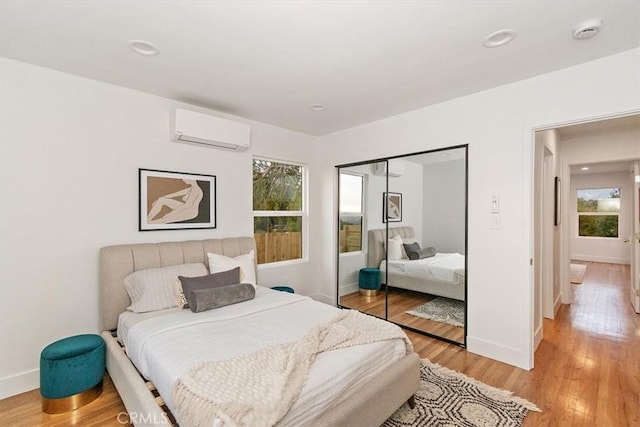 bedroom with a closet, light hardwood / wood-style floors, and a wall mounted AC