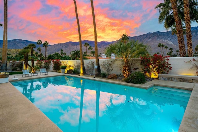 pool at dusk featuring a mountain view