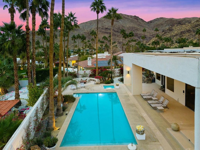 pool at dusk with a mountain view and a patio area