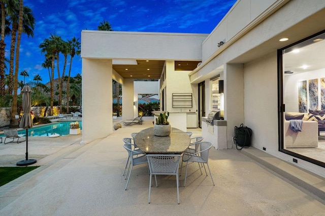 patio terrace at dusk featuring area for grilling