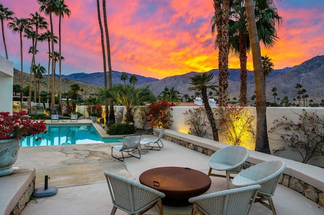 pool at dusk featuring a mountain view and a patio