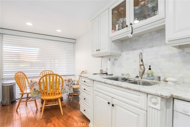 kitchen with light wood-style flooring, dishwasher, glass insert cabinets, and a sink