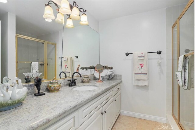 bathroom with a shower with door, vanity, and tile patterned flooring