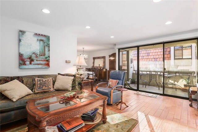 living room with hardwood / wood-style floors, a notable chandelier, and a wall of windows