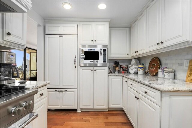 kitchen featuring tasteful backsplash, light hardwood / wood-style flooring, white cabinets, and appliances with stainless steel finishes