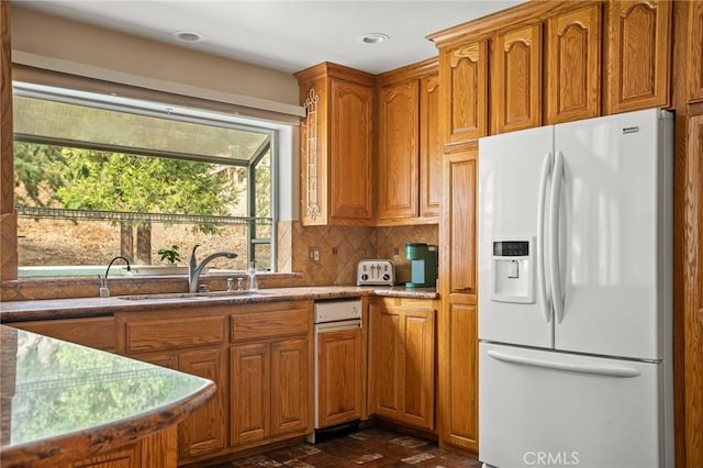 kitchen featuring white fridge with ice dispenser, sink, and backsplash